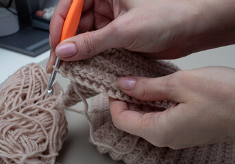 Woman knitting scarf with crochet hook close up