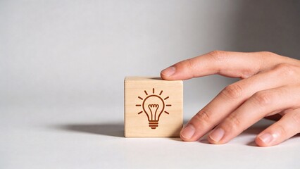 Hand holding wooden block with lightbulb icon