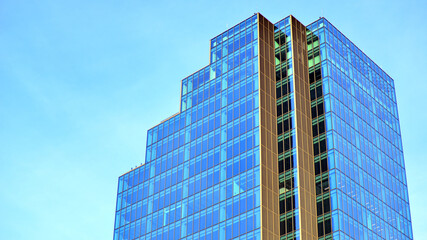 Obraz premium A modern tall building made of steel and glass, housing offices and financial institutions. Glass wall on the facade of the building.
