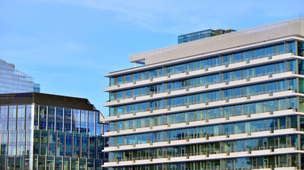 A modern tall building made of steel and glass, housing offices and financial institutions. Glass wall on the facade of the building.