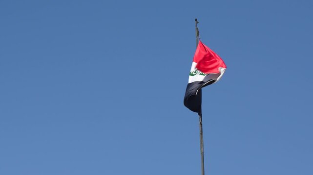 The Iraqi flag waving against the blue sky