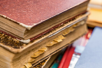 Several ancient books are lying on top of each other. One of the books has many bookmarks