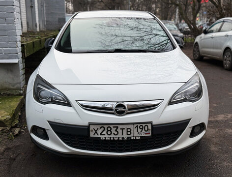 White Opel Astra J GTC in the city street. Motor sports car Opel Astra J GTC hot hatch in the city street. Opel Astra GTC OPC hatchback. German sport hatchback.