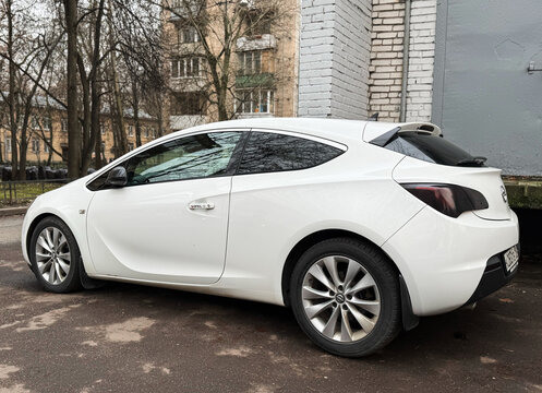 White Opel Astra J GTC in the city street. Motor sports car Opel Astra J GTC hot hatch in the city street. Opel Astra GTC OPC hatchback. German sport hatchback.