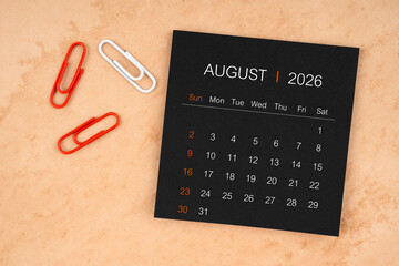 Black calendar sheet for August 2026 with paper clips on paper.