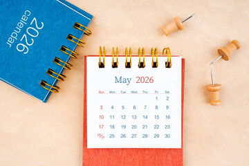 May 2026 desk calendar with wooden thumbtack on brown paper.