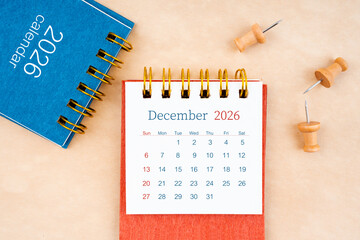 December 2026 desk calendar with wooden thumbtack on brown paper.