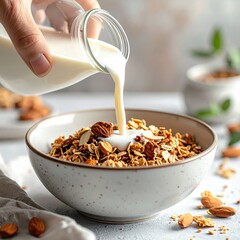 Pouring Creamy Almond Milk Over Healthy Granola Cereal with Nuts and Dried Fruit in a Bowl for Breakfast