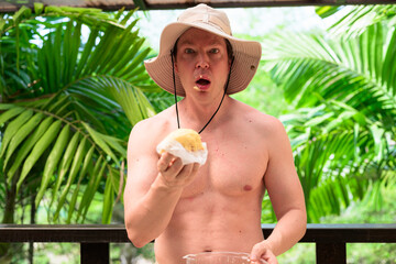 Scandinavian Tourist Man Eating Durian Outdoors with Tropical Leaves Background