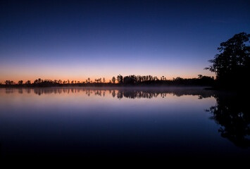 Obraz premium A beautiful lake with a sky full of stars. The sky is dark and the water is calm