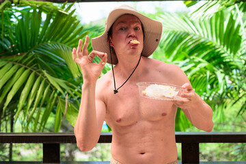 Scandinavian Tourist Man Eating Durian Outdoors with Tropical Leaves Background