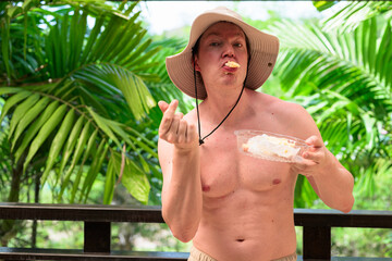Scandinavian Tourist Man Eating Durian Outdoors with Tropical Leaves Background