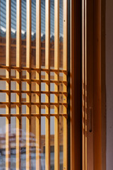 Wooden window frame detail, sunlight casting shadows through the lattice, creating a warm, inviting atmosphere.