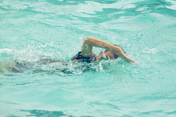 Asian child competing swimmer in the swimming pool