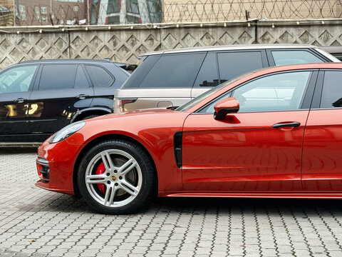  Hybrid Porsche Panamera 4S orange color parked at the city street. Orange car Porsche Panamera 4S on parking lot. The modern exterior of a premium German premium car. 