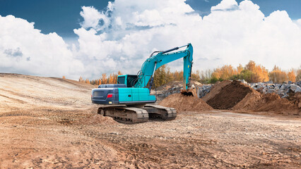 Obraz premium Excavator is digging into the ground at a construction site. Dirt piles up beside the machine. The sky is clear with some clouds and trees in the distance