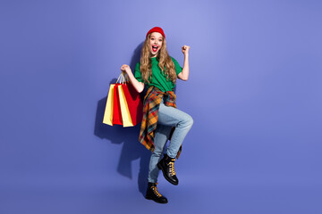 Happy young woman shopping in colorful casual outfit posing against blue background