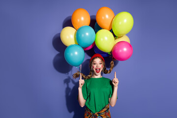 Young girl with colorful balloons celebrates joy and fun against a purple background wearing a...