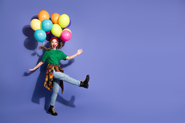 Young girl with colorful balloons leaping against a purple backdrop for a joyful fashion lifestyle...