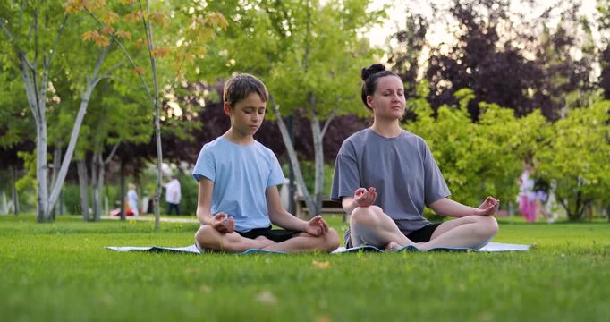 Adult guiding child through emotional regulation exercise outdoors. Stress management and emotional intelligence. Yoga, educational, mental wellbeing and balance. Mother and son at sunset in park.