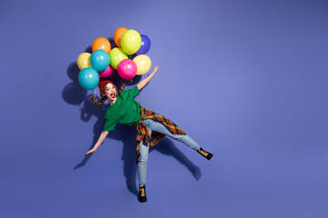 Young girl with colorful balloons floating in a blue studio backdrop for celebration and joy