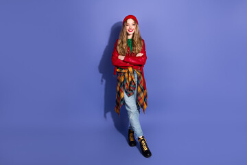 Fototapeta premium Young stylish woman model wearing red jacket plaid shirt and jeans posing with arms crossed against blue background