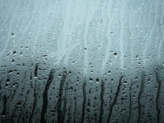 Window pane covered in condensation and raindrops, creating a blurred, abstract surface