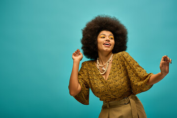 Stylish young woman dancing joyfully against a vibrant teal background