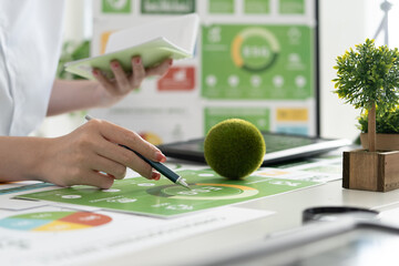 A diverse business team analyzing environmental charts and graphs in a collaborative meeting to create sustainable strategies in a modern office.
