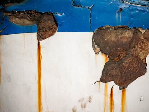 Peeling Paint on Old Metal Surface with Yellow Hinge and Rust Damage