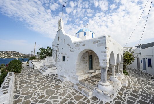 White Greek Orthodox Church Holy Church of Agios Konstantinos with Greek flag, Parikia, Paros, Cyclades, Greece