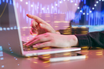 Person uses a laptop for trading with data visualizations and coins in the background during a business session