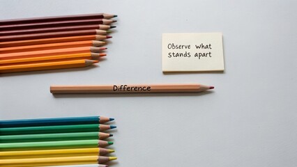 A single colored pencil labeled 'Difference' stands apart from a tonal arrangement of other pencils, with a sticky note prompting observation