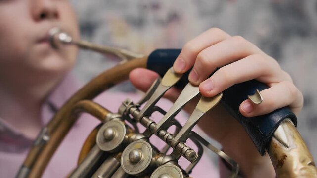 Home music practice with French horn. Close-up shot of teenager playing brass instrument as a hobby