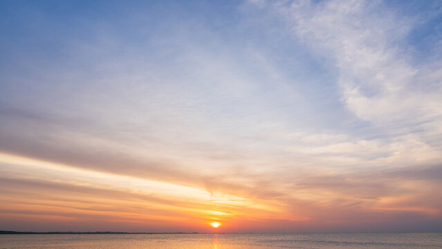 Sunset sky cloud sea water background in golden evening with orange, blue sun light,Horizon sea ocean sunrise sky landscape nature backgrounds warm gold sun down in golden hour summer season,Dusk sky