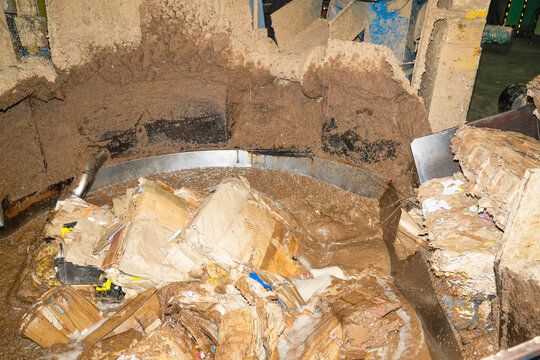 Cardboard boxes are broken down pulped with water in a large, circular tank. Paper recycling process at a recycling plant or factory.