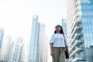 Fototapeta premium Modern urban lifestyle scene of solo woman in Tokyo city with skyscraper background, low angle view of high rise buildings in Tokyo