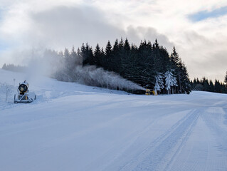 Snowmaking system operating along forested ski slope in Kopaonik. Artificial snow production, climate adaptation, and winter sport sustainability through technology and mountain infrastructure.