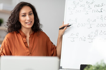 E-learning During Covid Lockdown. College professor teaching mathematics on web, conducting online class from home. Portrait of millennial teacher explaining math problems on internet using pc