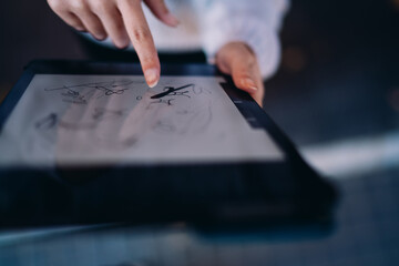Close-up of female hand drawing abstract shapes on tablet. Highlights tactile creativity, intuitive interaction, and fluid design process in digital art space.
