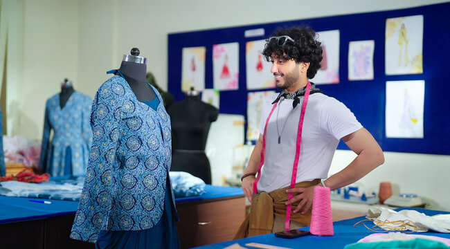 Indian happy young adult gen z male man wear tape around neck do work good indoor class room. Smart teen pupil boy do create new dummy dress clothe craft learn skill course day college place