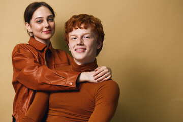 Young couple posing together with smiles and casual style against neutral background, woman hugging...