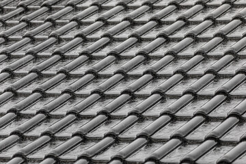 Black roof tiles in heavy rain, background texture
