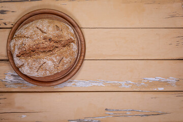 Rustic Homemade Bread On Round Wooden Board Over Worn Beige Table
