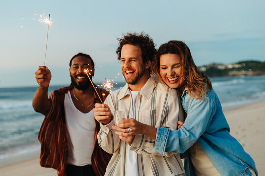 Friends celebrating with sparklers on the beach during a festive evening