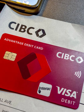 Bratislava, Slovakia, Europe - Jan 17, 2026: CIBC Visa debit card beside smartphone showing banking app, representing digital payments, personal finance, and modern Canadian banking technology.