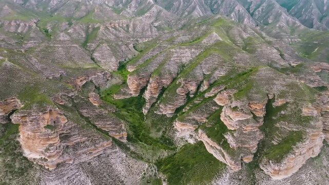Drone footage captures the stunning, arid landscape and unique rock formations of the Chongkatau mountain range in the Republic of Dagestan, Russia. A beautiful natural background showcasing the remot