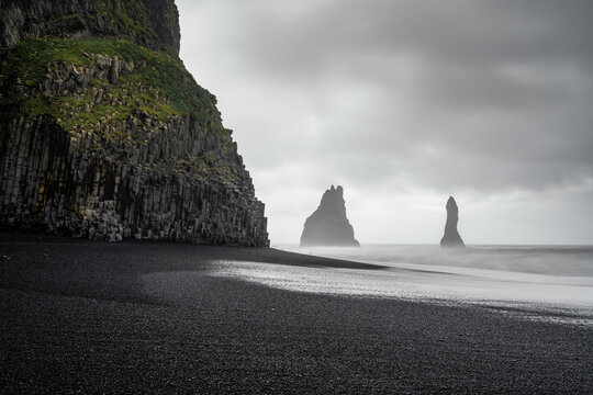 view of the Reynisfjara Black Sand beach with the landmark basalt columns and the Reynisdrangar sea stack - Powered by Adobe