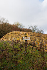 Danger sign and fence on old stone canal bridge crossing abandoned Somerset Coal Canal, England