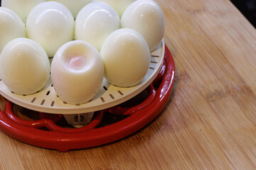 Round tray of white shelled hard-boiled eggs one with yolk showing